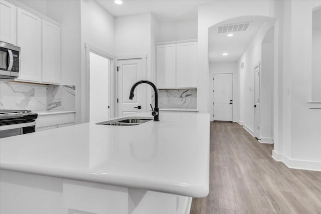 8609 San Giano Cv, Round Rock, TX 78665 - kitchen with stainless steel microwave, arched walkways, white cabinetry, recessed lighting, and light countertops