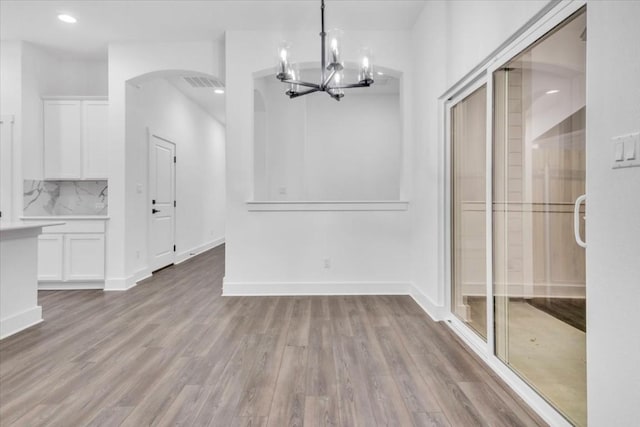 8609 San Giano Cv, Round Rock, TX 78665 - unfurnished dining area featuring a chandelier, wood finished floors, arched walkways, and recessed lighting