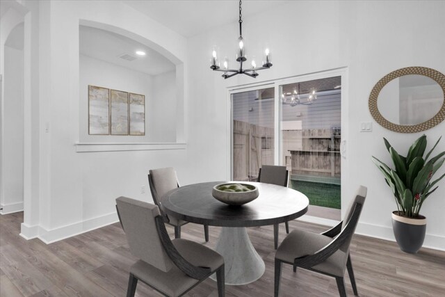 8609 San Giano Cv, Round Rock, TX 78665 - dining room with arched walkways, a chandelier, and wood finished floors