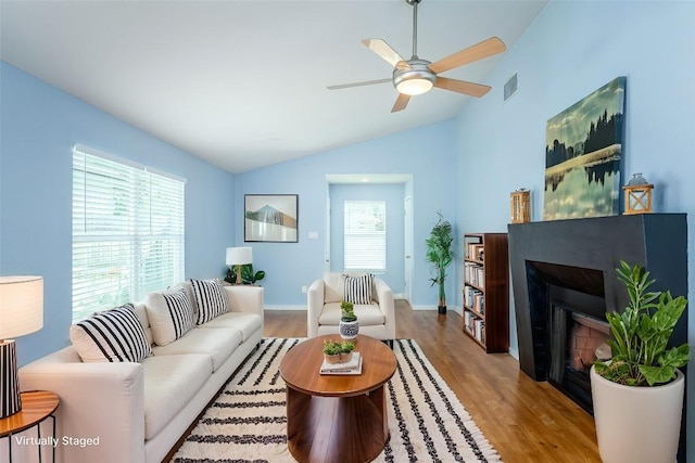 5909 Kevin Kelly Pl, Austin, TX 78727 - living area featuring wood finished floors, vaulted ceiling, a glass covered fireplace, and a ceiling fan