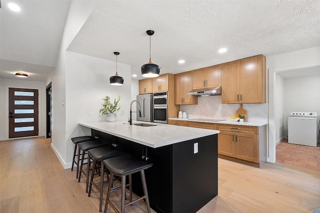 506 Explorer, Lakeway, TX 78734 - kitchen with washer / clothes dryer, under cabinet range hood, a kitchen breakfast bar, a peninsula, and appliances with stainless steel finishes