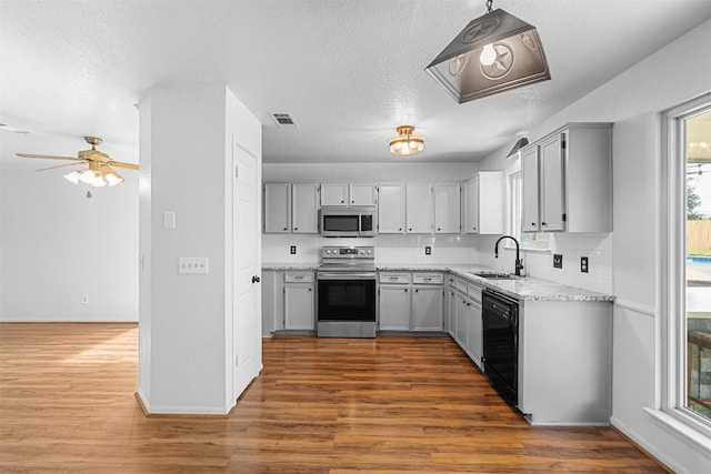506 Turtle Back Cv, Killeen, TX 76542 - kitchen with appliances with stainless steel finishes, a ceiling fan, wood finished floors, a textured ceiling, and light stone counters