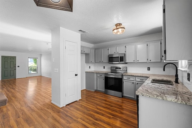 506 Turtle Back Cv, Killeen, TX 76542 - kitchen featuring stainless steel appliances, dark wood-type flooring, gray cabinetry, light stone countertops, and a textured ceiling