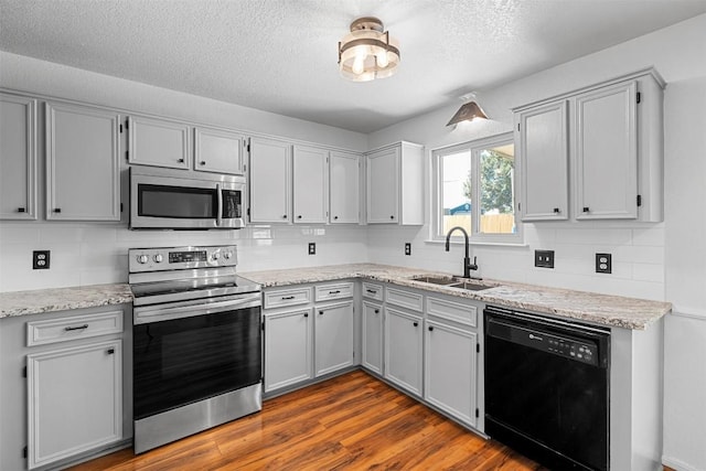 506 Turtle Back Cv, Killeen, TX 76542 - kitchen featuring appliances with stainless steel finishes, a textured ceiling, tasteful backsplash, dark wood-type flooring, and light stone countertops