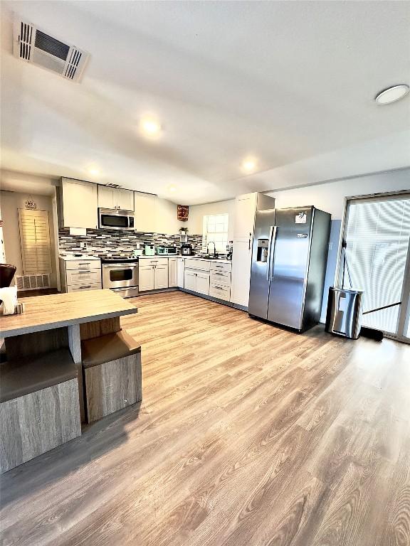 149 Gato Rd, Cedar Creek, TX 78612 - kitchen with stainless steel appliances, light wood-style flooring, backsplash, and recessed lighting