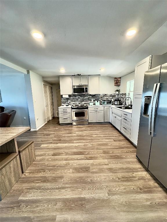 149 Gato Rd, Cedar Creek, TX 78612 - kitchen featuring stainless steel appliances, light countertops, backsplash, wood finished floors, and recessed lighting