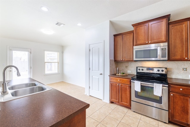 18824 Keeli Ln, Pflugerville, TX 78660 - kitchen featuring appliances with stainless steel finishes, dark countertops, backsplash, and light tile patterned flooring