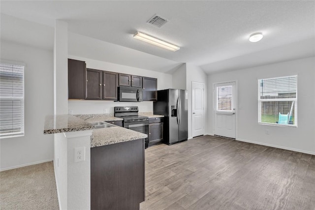 14802 Tuff Rd, Manor, TX 78653 - kitchen featuring black appliances, dark brown cabinetry, light stone countertops, vaulted ceiling, and a peninsula
