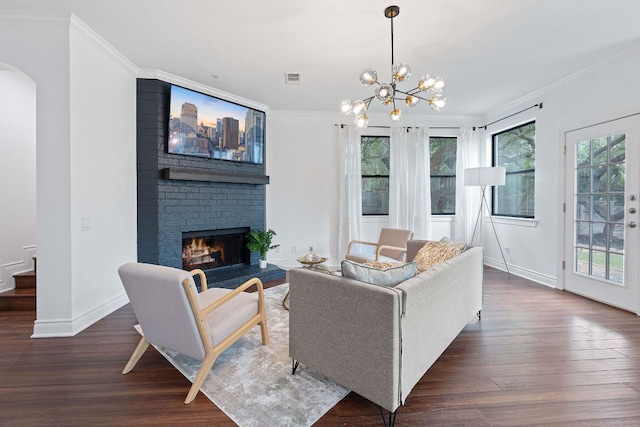 9402 Caracas Dr, Austin, TX 78733 - living room with crown molding, dark wood finished floors, arched walkways, a brick fireplace, and a chandelier