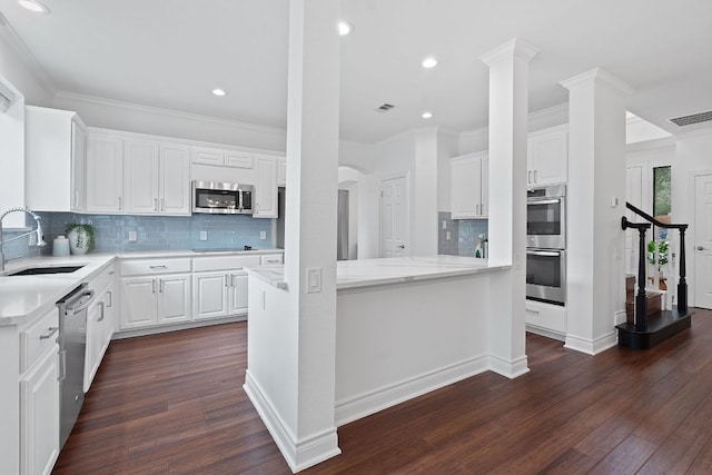 9402 Caracas Dr, Austin, TX 78733 - kitchen featuring appliances with stainless steel finishes, dark wood-style flooring, decorative backsplash, white cabinetry, and ornamental molding