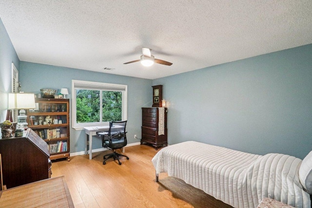 428 Gotier Trace Rd, Smithville, TX 78957 - bedroom with wood finished floors, a textured ceiling, a ceiling fan, and a desk