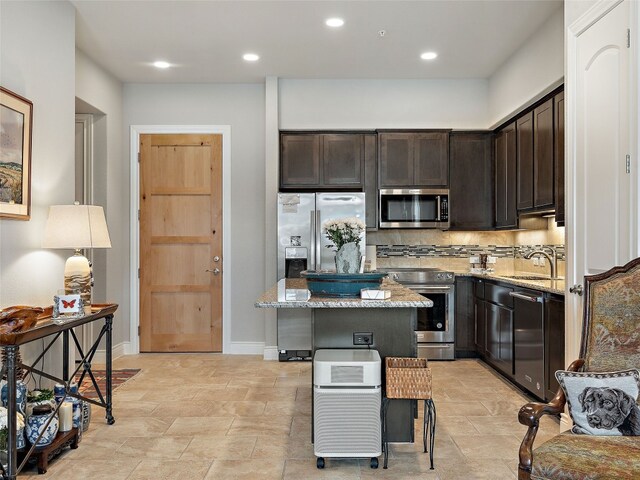 106 Bella Toscana Ave Unit 3204, Lakeway, TX 78734 - kitchen featuring stainless steel appliances, light stone counters, a center island, dark brown cabinetry, and tasteful backsplash