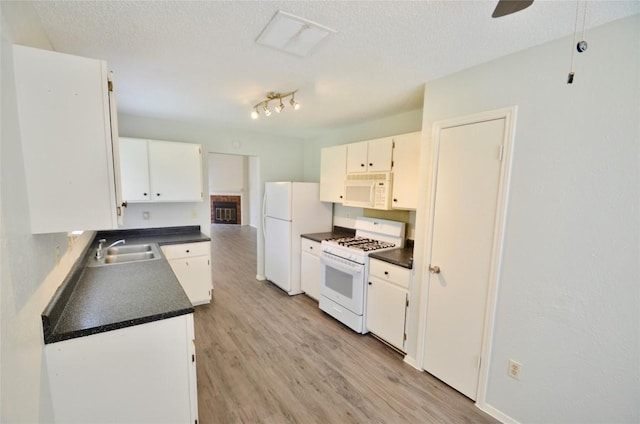 2200 Frontier Trl, Round Rock, TX 78681 - kitchen featuring white appliances, dark countertops, light wood finished floors, a textured ceiling, and white cabinets