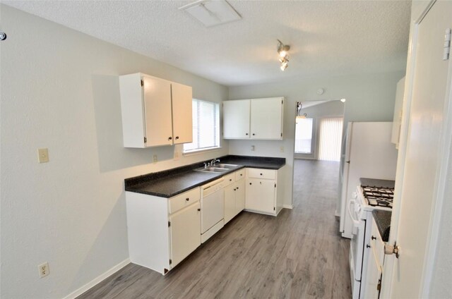 2200 Frontier Trl, Round Rock, TX 78681 - kitchen featuring white appliances, a textured ceiling, light wood-type flooring, white cabinets, and dark countertops