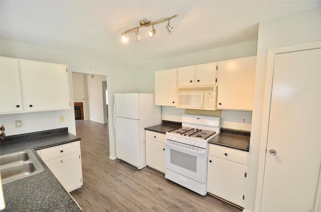 2200 Frontier Trl, Round Rock, TX 78681 - kitchen with white appliances, dark countertops, light wood-style flooring, and white cabinets
