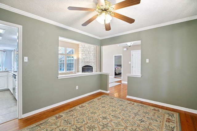 148 Oak Ridge Dr, Cedar Creek, TX 78612 - empty room with wood finished floors, a brick fireplace, ceiling fan, and ornamental molding