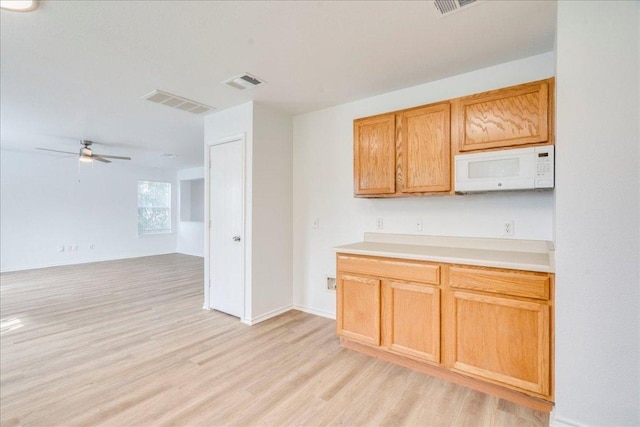 618 Lavaca Loop, Elgin, TX 78621 - kitchen featuring white microwave, light wood finished floors, ceiling fan, light countertops, and open floor plan