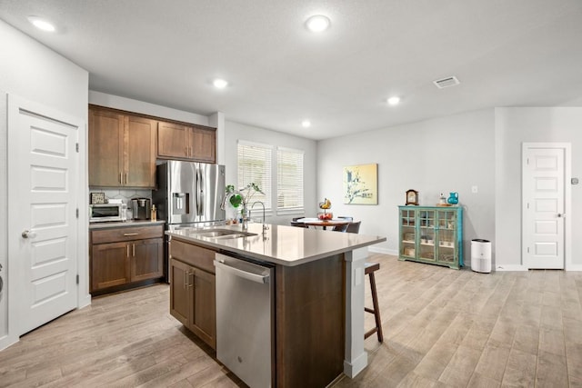 2705 Grizzly Way, Leander, TX 78641 - kitchen with appliances with stainless steel finishes, light wood-type flooring, an island with sink, recessed lighting, and a breakfast bar area
