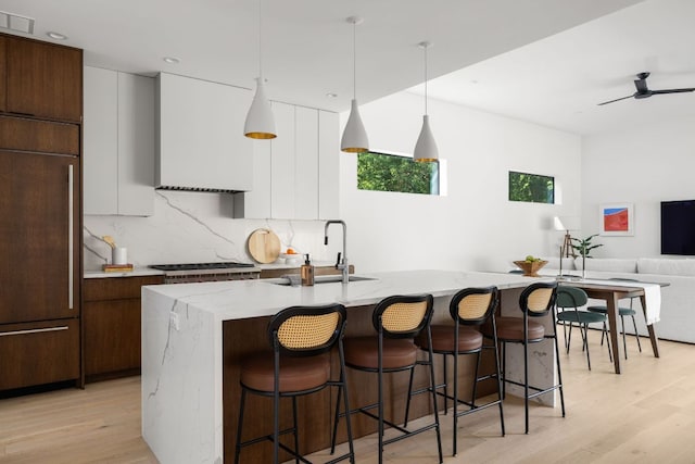1911 Piedmont Ave, Austin, TX 78757 - kitchen featuring modern cabinets, light wood-style flooring, a breakfast bar, tasteful backsplash, and recessed lighting