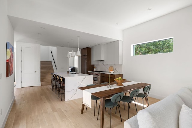 1911 Piedmont Ave, Austin, TX 78757 - kitchen with high end range, light wood-style flooring, modern cabinets, tasteful backsplash, and hanging light fixtures