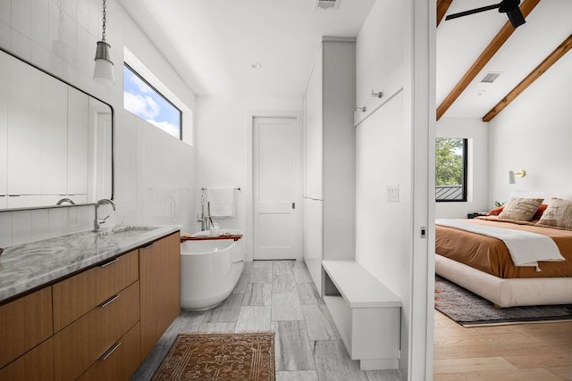 1911 Piedmont Ave, Austin, TX 78757 - bathroom featuring a freestanding bath, vanity, beamed ceiling, and wood finished floors