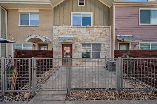 1101 Grove Blvd Unit 206, Austin, TX 78741 - view of property featuring stone siding, board and batten siding, a gate, and a fenced front yard
