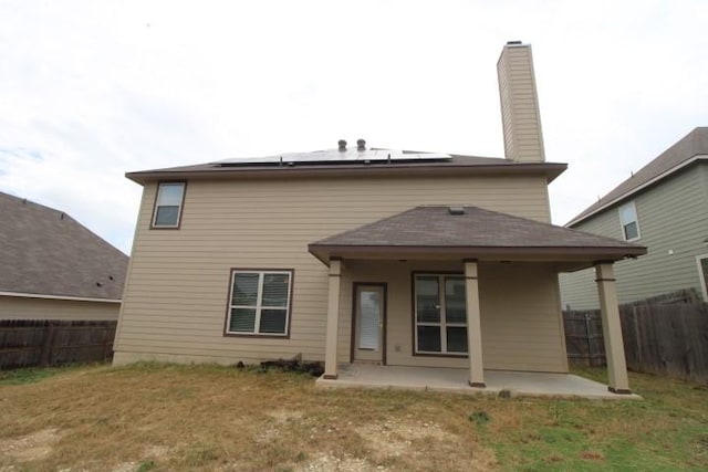 861 Stockdale Rd, Copperas Cove, TX 76522 - rear view of house with a patio, roof mounted solar panels, a fenced backyard, and a chimney