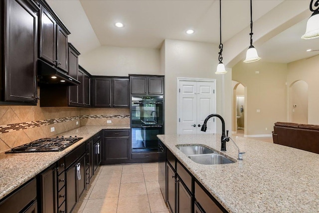 2944 Saint Federico Way, Round Rock, TX 78665 - kitchen with black appliances, arched walkways, under cabinet range hood, decorative backsplash, and light stone countertops