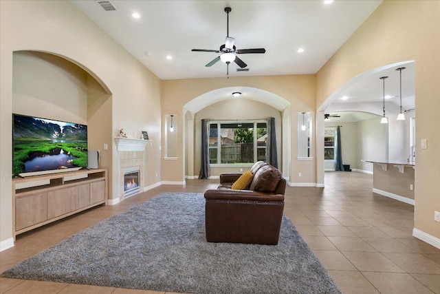 2944 Saint Federico Way, Round Rock, TX 78665 - living room with a ceiling fan, tile patterned floors, a tile fireplace, arched walkways, and recessed lighting