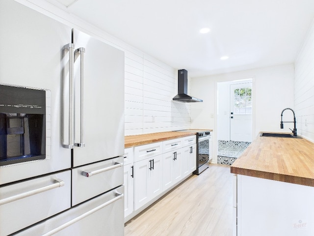 6108 Shadow Valley Dr Unit A, Austin, TX 78731 - kitchen featuring high end white fridge, wood counters, wall chimney range hood, stainless steel stove, and white cabinetry