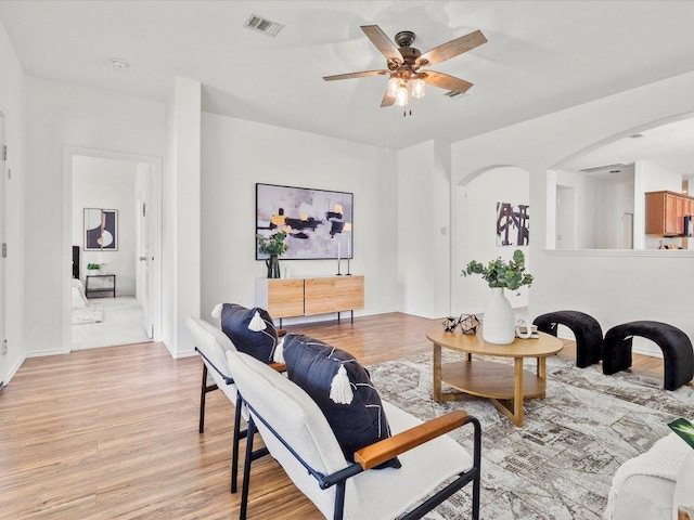 310 Comal Run, Hutto, TX 78634 - living room with arched walkways, light wood finished floors, and a ceiling fan