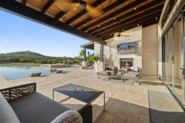 101 Rolling Hills Rd, Blanco, TX 78606 - view of patio / terrace with a water view, an outdoor living space with a fireplace, and ceiling fan