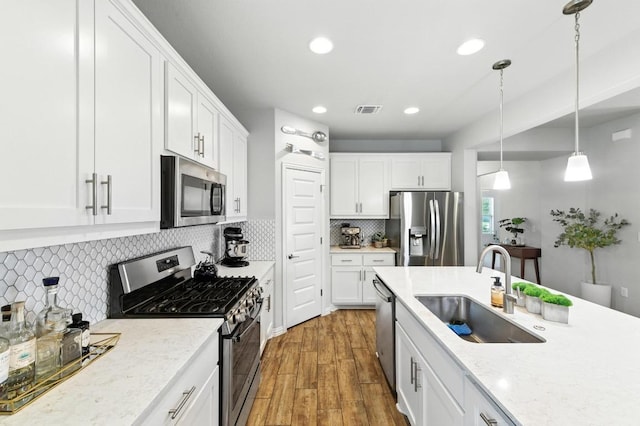 5512 Baythorne Dr, Austin, TX 78747 - kitchen featuring appliances with stainless steel finishes, white cabinets, wood finished floors, recessed lighting, and pendant lighting