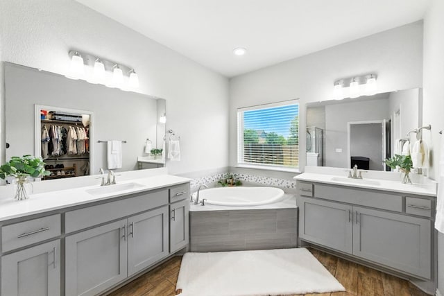 5512 Baythorne Dr, Austin, TX 78747 - full bath featuring two vanities, a shower stall, a bath, wood finished floors, and a walk in closet