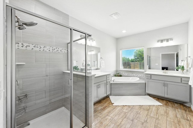 5512 Baythorne Dr, Austin, TX 78747 - bathroom with two vanities, a shower stall, a bath, wood finished floors, and recessed lighting