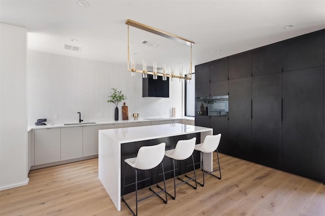 1203 Richcreek Rd, Austin, TX 78757 - kitchen with light wood-style floors, light countertops, a breakfast bar area, and pendant lighting