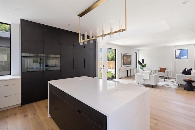 1203 Richcreek Rd, Austin, TX 78757 - kitchen with light wood-style floors, a center island, modern cabinets, dark cabinets, and recessed lighting