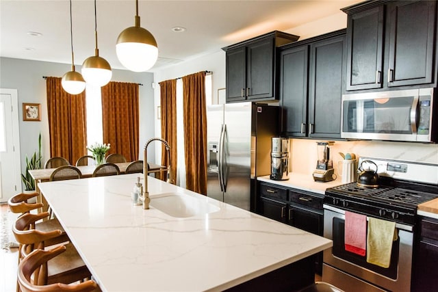 1510 Homespun Rd Unit 79, Austin, TX 78745 - kitchen featuring appliances with stainless steel finishes, a kitchen bar, a kitchen island with sink, and dark cabinets