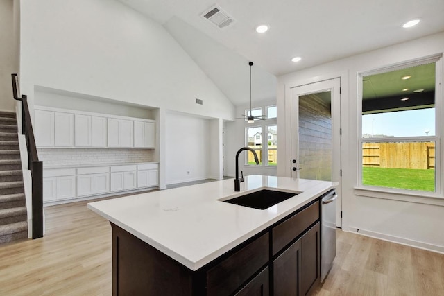 596 Biscayne Bay Bnd, Kyle, TX 78640 - kitchen with light wood-style flooring, light countertops, dark brown cabinets, decorative backsplash, and hanging light fixtures