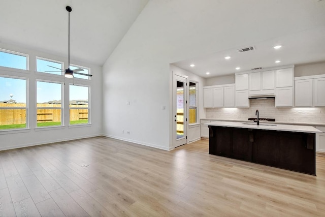 596 Biscayne Bay Bnd, Kyle, TX 78640 - kitchen with light countertops, high vaulted ceiling, decorative backsplash, white cabinets, and light wood-style floors