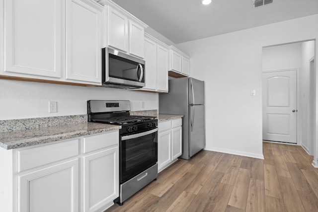 384 Low Pasture Trl, San Marcos, TX 78656 - kitchen with stainless steel appliances, white cabinetry, light wood-type flooring, and light stone countertops