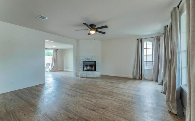 1623 Peachtree Valley Dr, Round Rock, TX 78681 - unfurnished living room featuring a ceiling fan, healthy amount of natural light, wood finished floors, and a stone fireplace