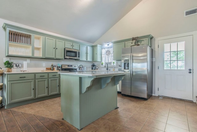 14596 Touchstone Rd Unit 3, Atascosa, TX 78002 - kitchen featuring appliances with stainless steel finishes, green cabinetry, light countertops, high vaulted ceiling, and a breakfast bar