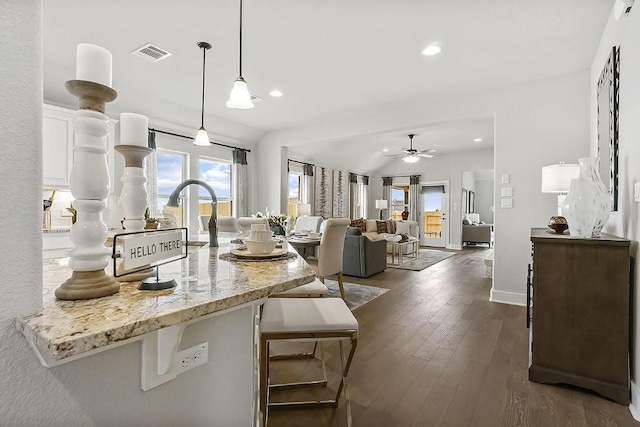 113 Charro Ct, Georgetown, TX 78633 - kitchen with white cabinets, dark wood-type flooring, a kitchen breakfast bar, a ceiling fan, and light stone countertops