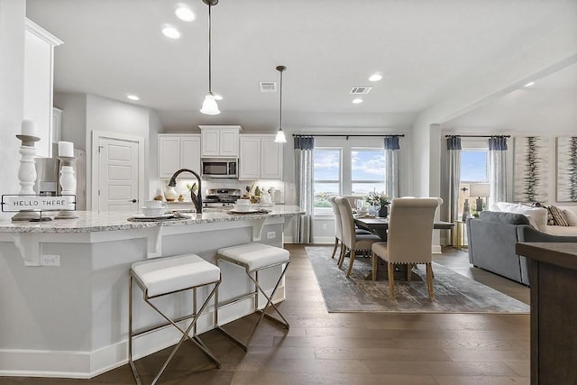 113 Charro Ct, Georgetown, TX 78633 - kitchen with appliances with stainless steel finishes, plenty of natural light, dark wood-style flooring, a breakfast bar, and recessed lighting