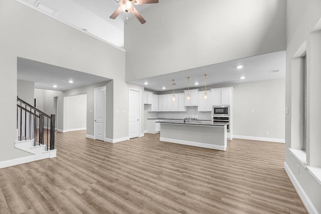 109 Charro Ct, Georgetown, TX 78633 - unfurnished living room featuring ceiling fan, a high ceiling, light wood finished floors, stairs, and recessed lighting