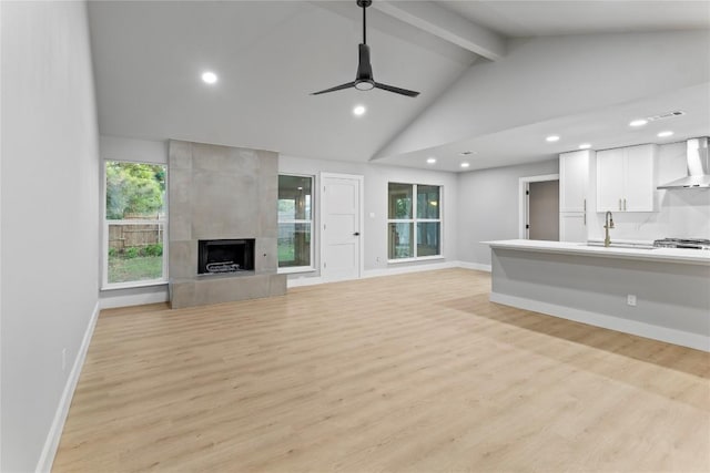 3907 Carmel Dr, Austin, TX 78721 - unfurnished living room with beamed ceiling, a ceiling fan, light wood-style floors, a fireplace, and recessed lighting