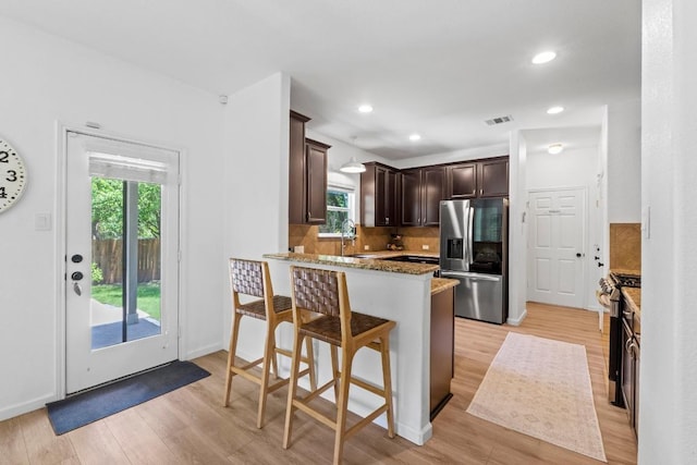 1620 Rockland Dr Unit 167, Austin, TX 78748 - kitchen with stainless steel appliances, dark brown cabinets, light wood finished floors, decorative backsplash, and a peninsula