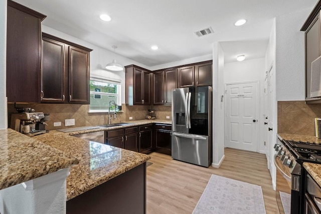 1620 Rockland Dr Unit 167, Austin, TX 78748 - kitchen featuring stainless steel appliances, dark brown cabinetry, light stone countertops, backsplash, and light wood-style flooring
