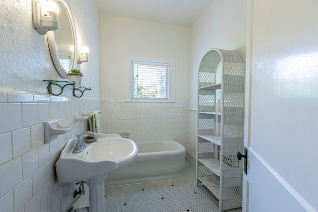 618 N Penelope St, Belton, TX 76513 - bathroom featuring tile walls, a wainscoted wall, radiator, and a tub to relax in